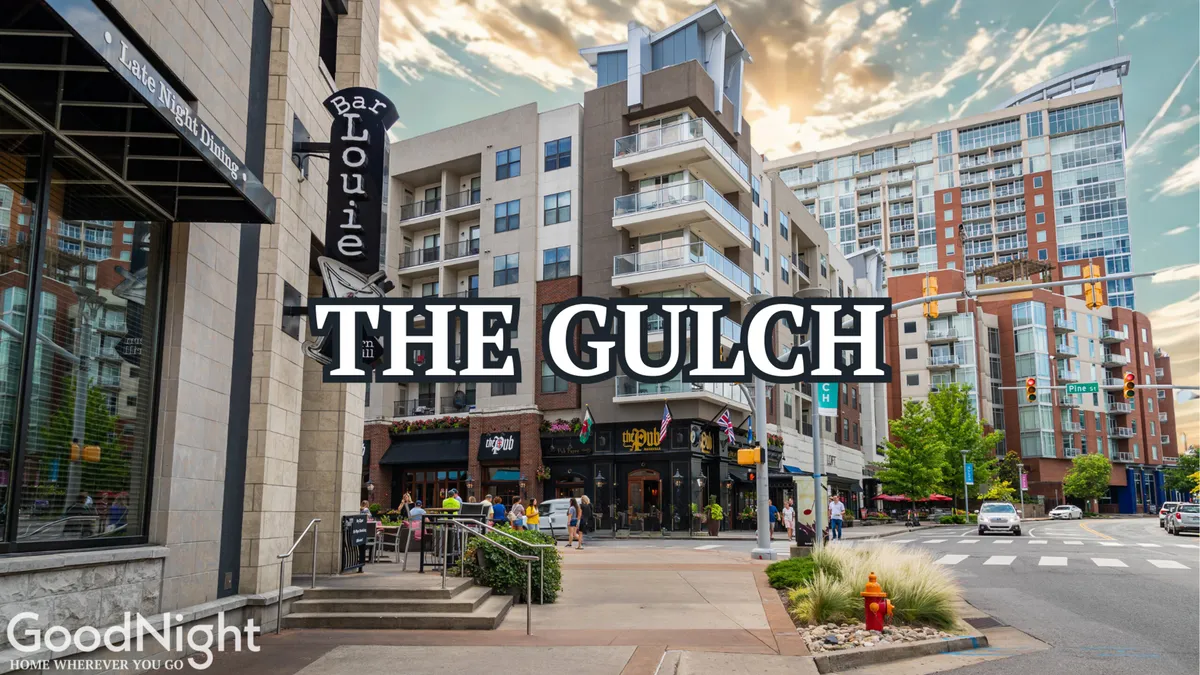 A lively street scene in the heart of The Gulch, featuring Bar Louie, prominent Gulch signage, modern apartment buildings, and people engaged in dining, shopping, and strolling along the pedestrian paths. The overall atmosphere is vibrant and social, capturing the essence of a walkable urban entertainment district.